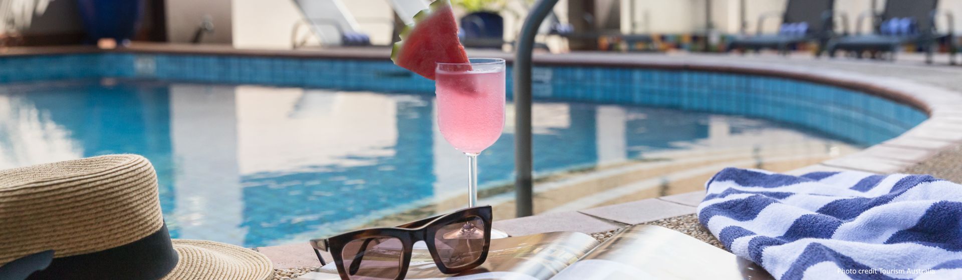 Closeup of sunglasses on a magazine on the ground paired with a watermelon cocktail at the pool area at Rydges Darwin Central, Northern Territory, Australia