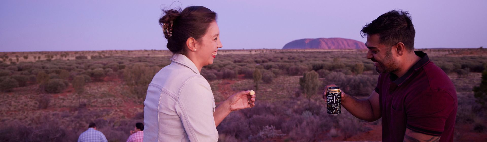 A couple enjoying their dinner basket with Uluru in the background, Northern Territory, Australia