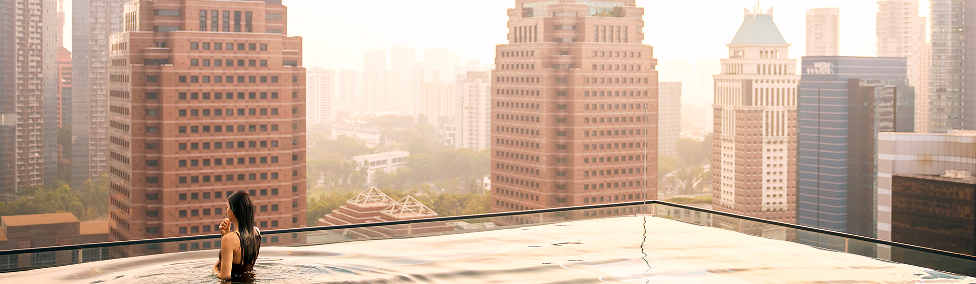 A woman standing in the Infinity Pool at the rooftop of COMO Metropolitan Singapore Hotel