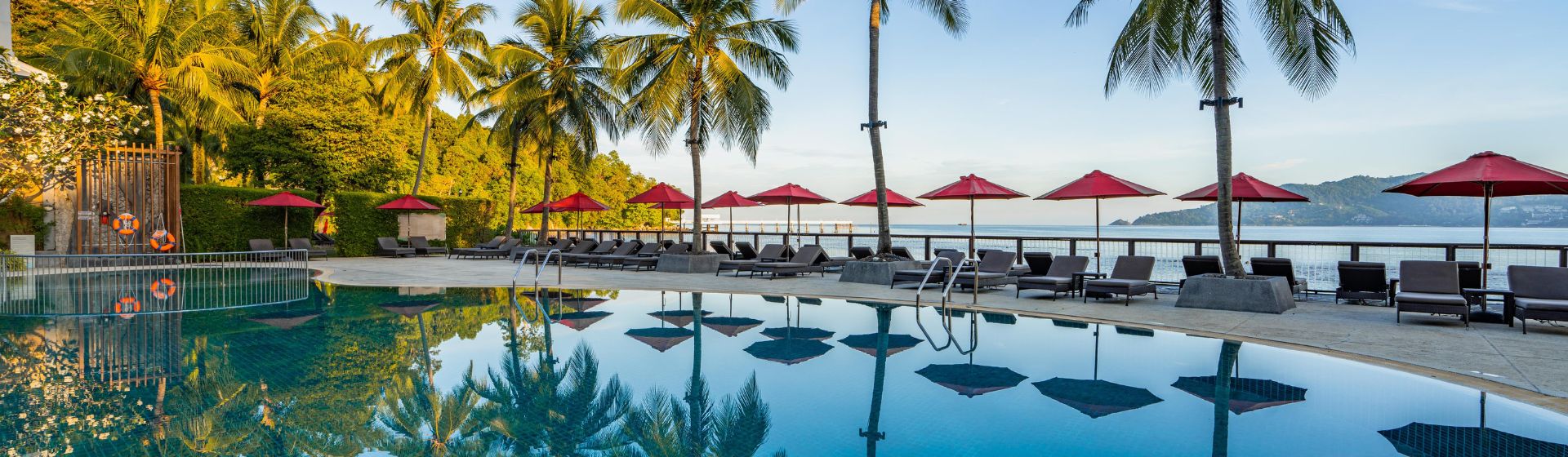 Amari Phuket pool view with sun lounges and umbrellas, located adjacent to the beach