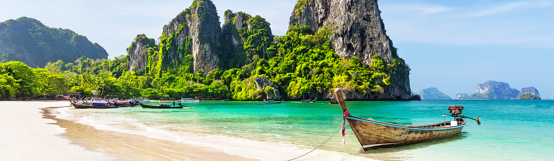 A traditional Thai boat docked at a secluded bay with striking karsts in the ocean, Thailand