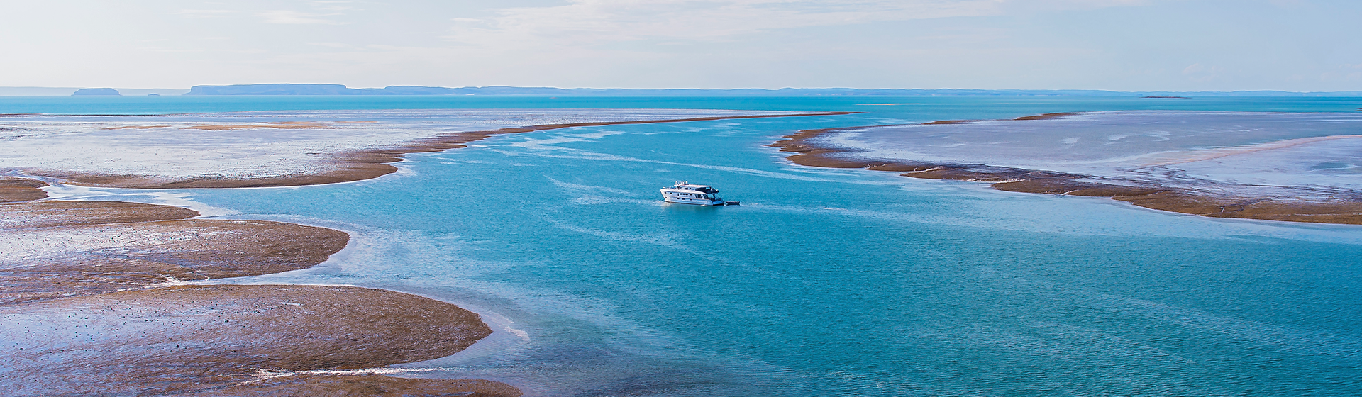 A small boat cruising along Montgomery Reef, off the Kimberley coast of Western Australia