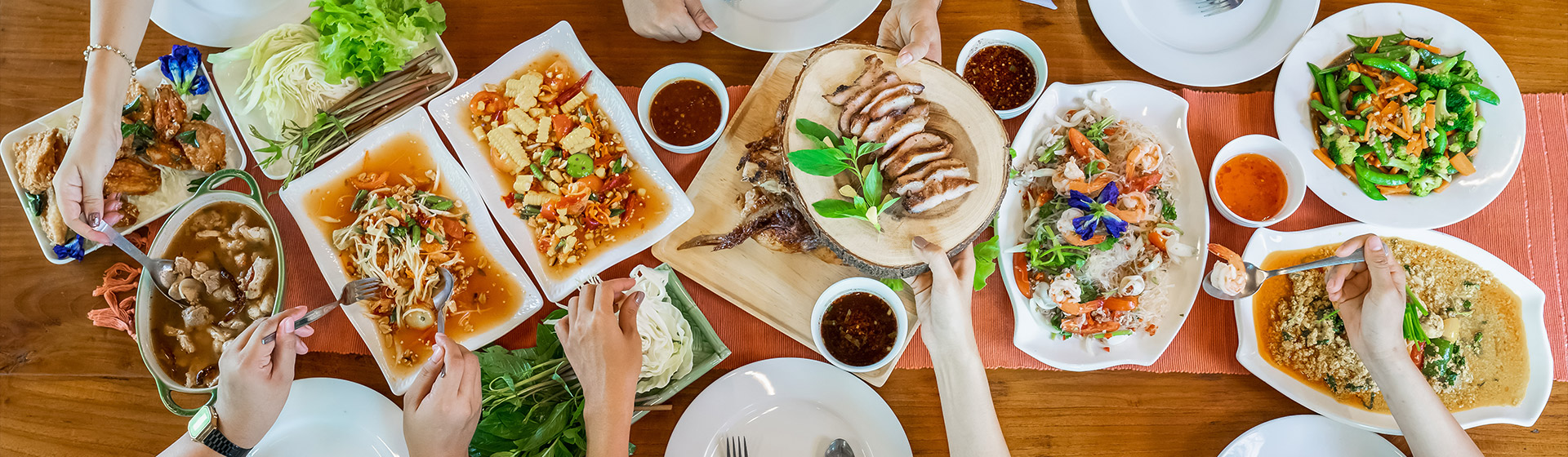 A group of people seated around a table sharing some Thai dishes